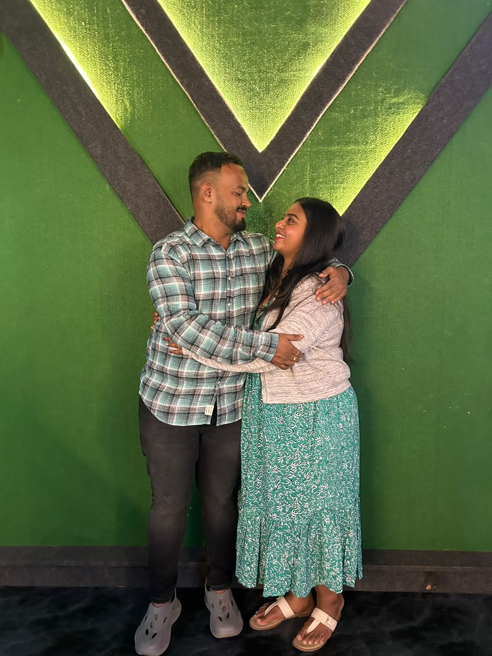 Pradeep and Ananya embracing by a green wall
